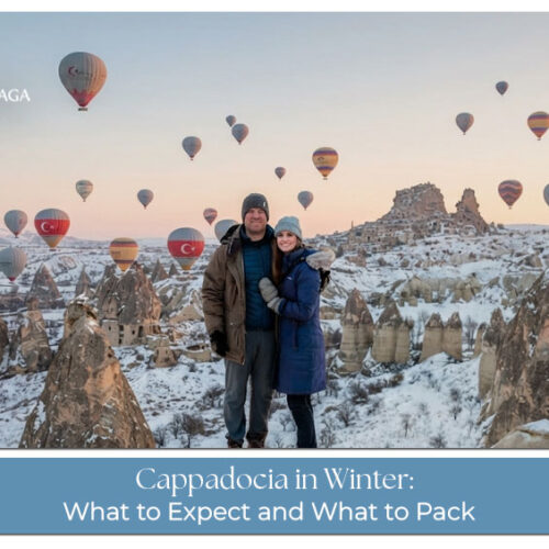 Snow-covered Cappadocia landscape with hot air balloons floating above the winter valleys.